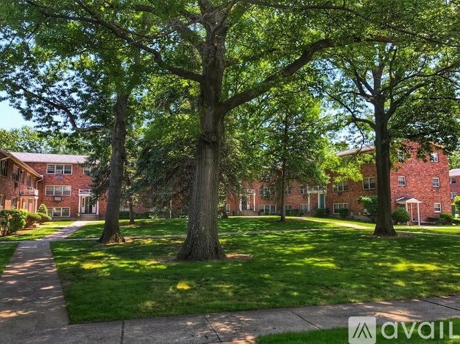 A tree-lined pathway leads to a brick building.