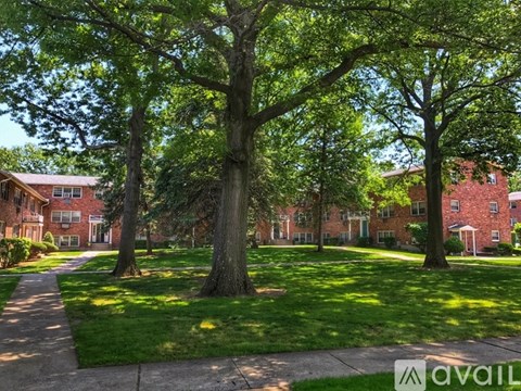 A tree-lined pathway leads to a brick building.
