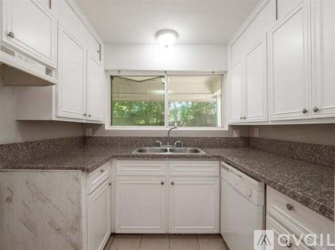 A kitchen with white cabinets and a granite countertop.