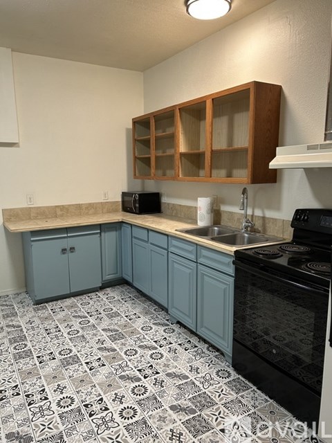 A kitchen with a black oven and blue cabinets.