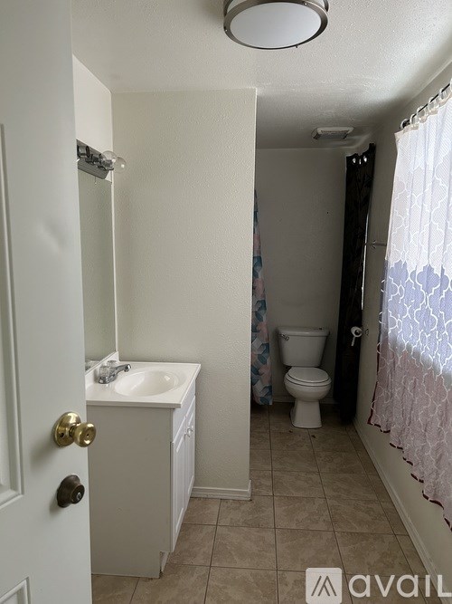 A bathroom with a toilet, sink, and shower curtain.