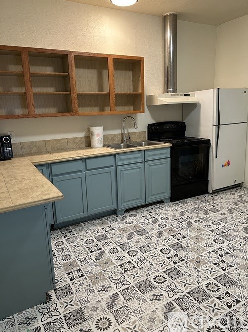 A kitchen with a black oven and a white fridge.
