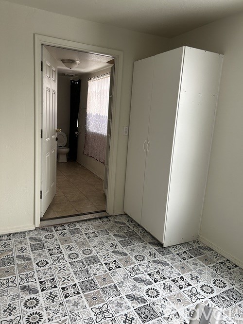 A white closet with a mirrored door is open to a bathroom.