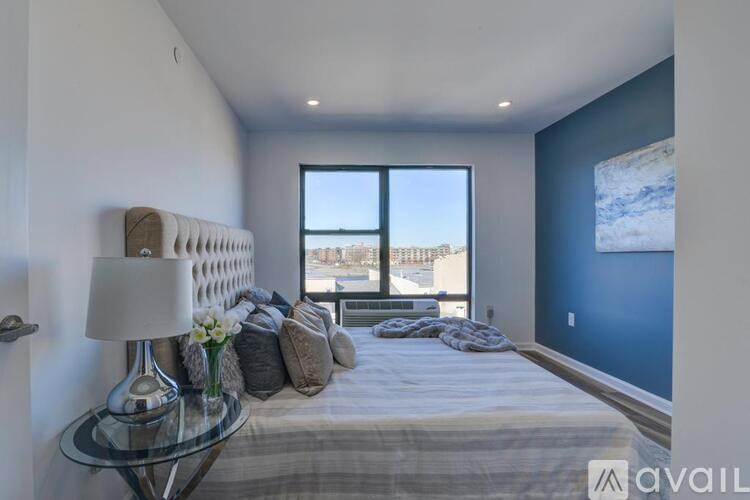 A bedroom with a bed, a lamp, and a window overlooking a cityscape.