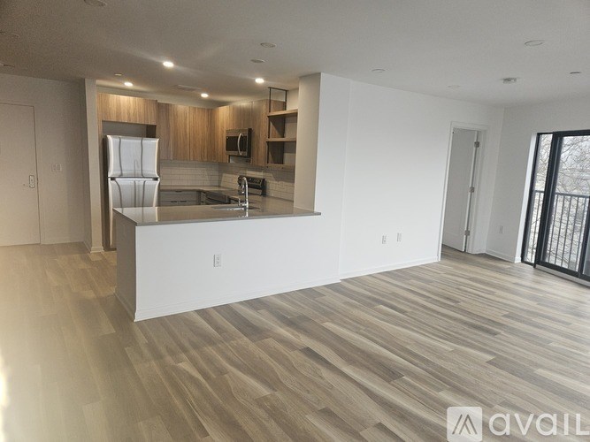 A spacious kitchen with wooden flooring and modern appliances.