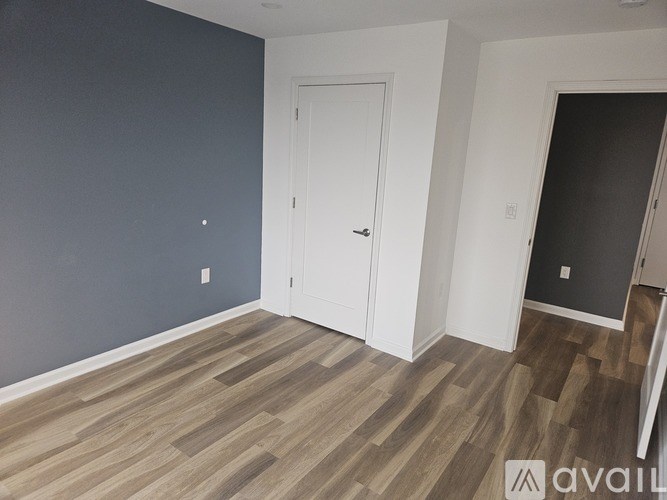 A room with a white door and wooden flooring.