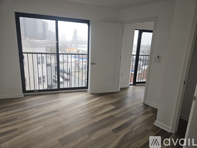 A room with wooden flooring and a balcony with a railing.
