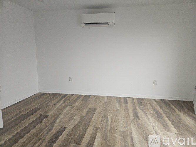 A room with wooden flooring and an air conditioner mounted on the wall.