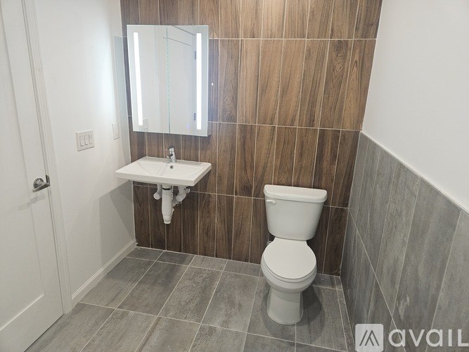 A bathroom with a toilet, sink, and mirror.