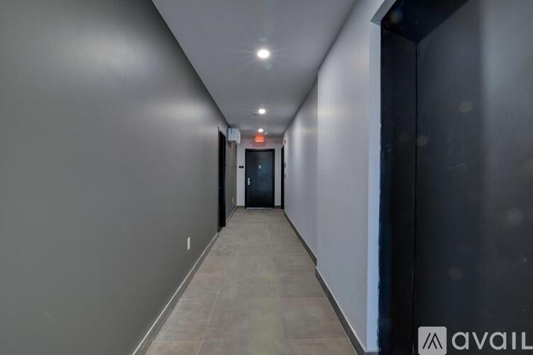 A long hallway with a door at the end and a sign above it.