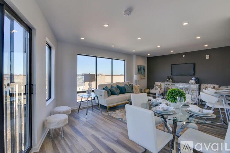 A modern dining room with a glass table and white chairs.