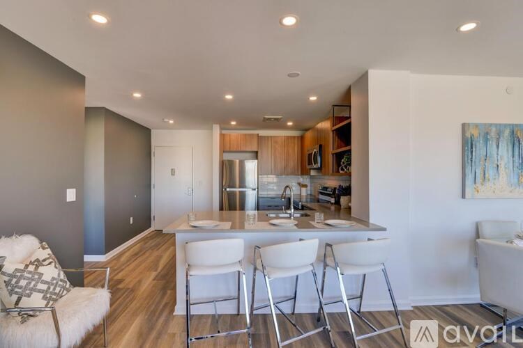 A modern kitchen with white chairs and a wooden counter.