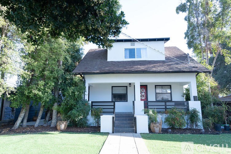 A white house with a red door and a brown roof.