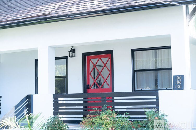 A white house with a red door and a black bench in front.