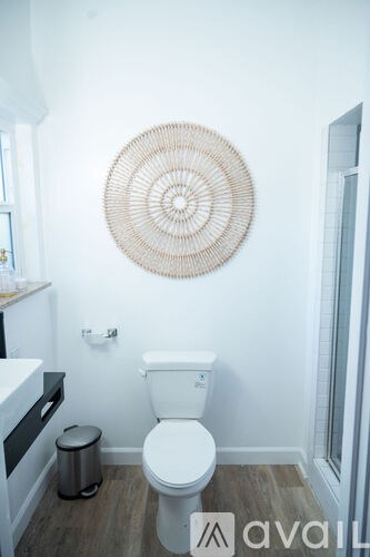 A white toilet in a bathroom with a woven circle on the wall.