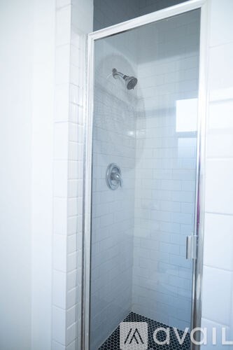 A glass shower door with a handle and a shower head.