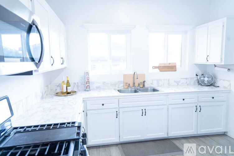 A kitchen with white cabinets and a black fridge.