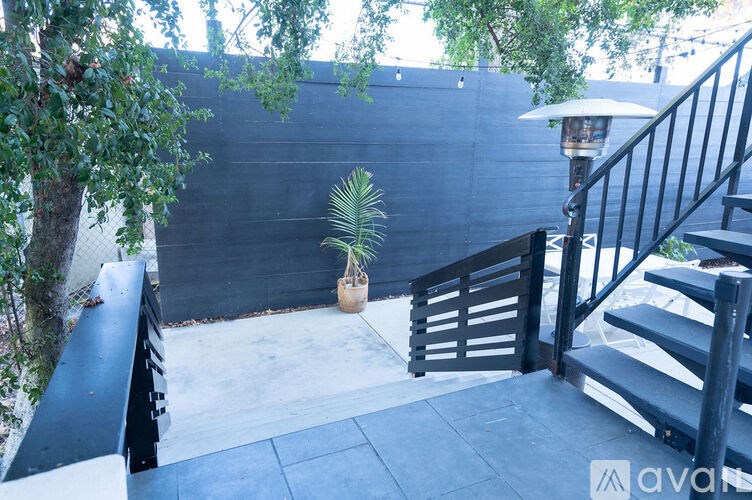 A patio with a black railing and a potted plant.