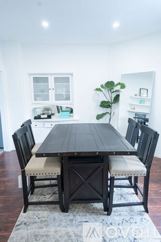A dining table with chairs and a rug in the middle of the room.