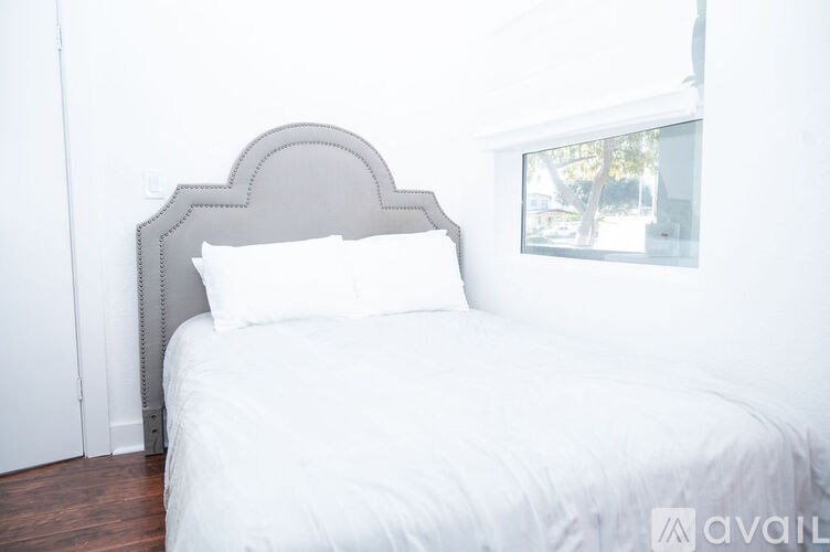 A white bed with a grey headboard and pillow in a room.