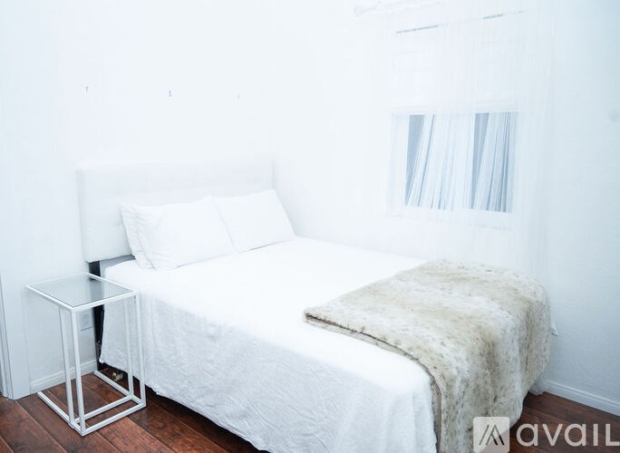 A white bed with a white headboard and a white bedspread with a white pillow and a white bedroom.