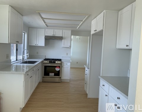 A kitchen with white cabinets and a wooden floor.