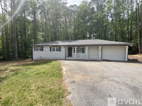 A house with a garage is surrounded by trees.