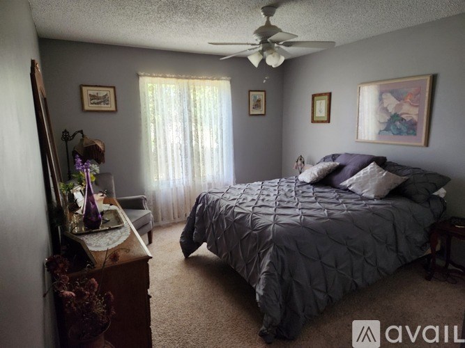 A bedroom with a large bed and a ceiling fan.