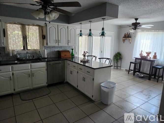 A kitchen with white cabinets and a black counter top.