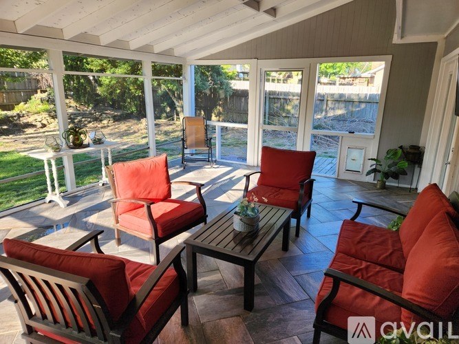 A patio with red cushions and a table with a vase of flowers on it.
