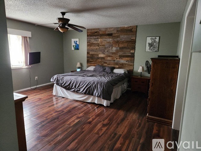 A bedroom with a bed, dresser, and a ceiling fan.