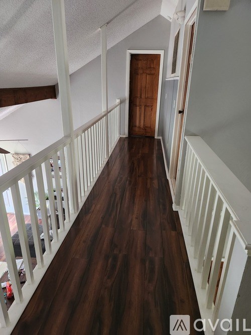 A long hallway with a wooden floor and white railings.