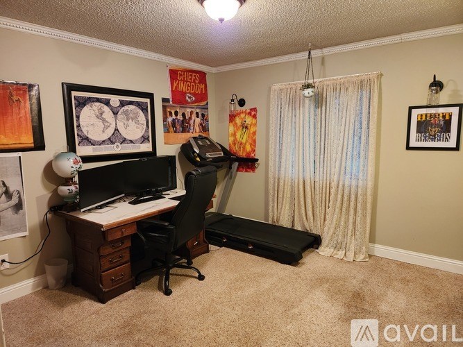 A room with a desk, chair, and a poster on the wall.