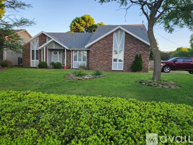 A house with a well-maintained lawn and a tree in front.