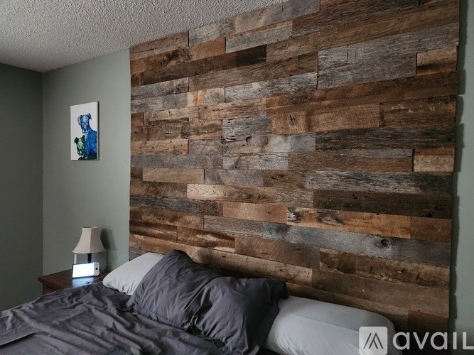 A bedroom with a wooden headboard and a bed with a grey comforter.