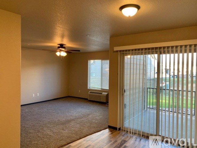A room with a ceiling fan and sliding glass doors.