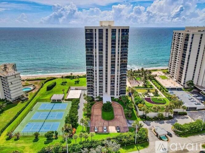 A beachfront hotel with a tennis court in the foreground.