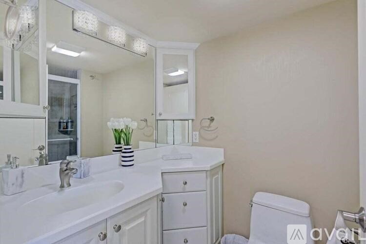 A white bathroom with a vanity, toilet, and a mirror.