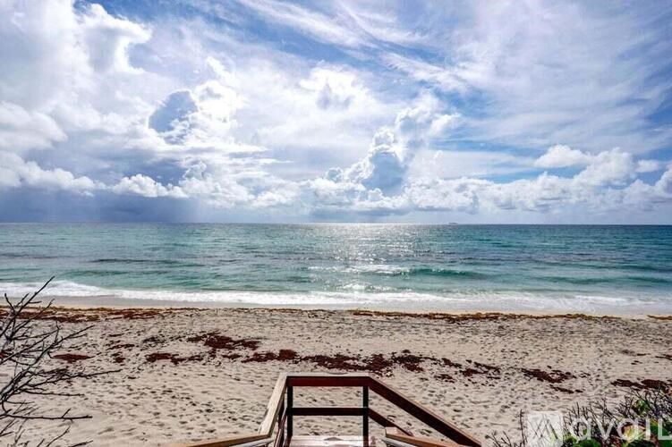 A beach scene with a cloudy sky and a railing in the foreground.