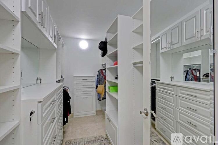 A white walk-in closet with a mirror and drawers.