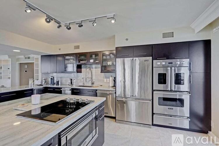 A modern kitchen with stainless steel appliances and a marble countertop.