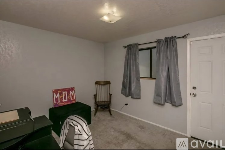 A room with a green couch, a chair, a window with curtains, and a sign that says "MOM".