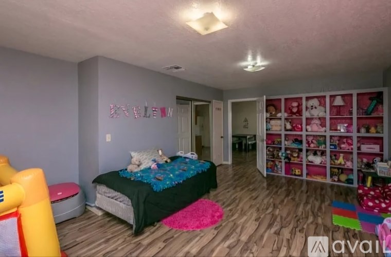 A child's bedroom with a bed, toy storage, and a play area.