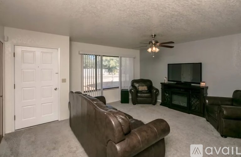 A living room with a brown couch, a television, and a ceiling fan.