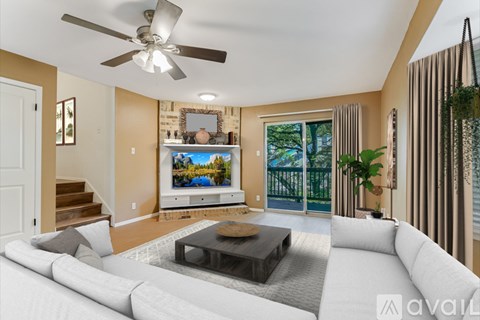 A living room with a white couch and a flat screen TV mounted on the wall.
