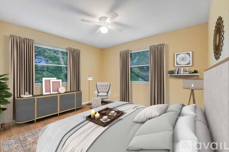 A bedroom with a large bed, a chair, a side table, and a window with curtains.