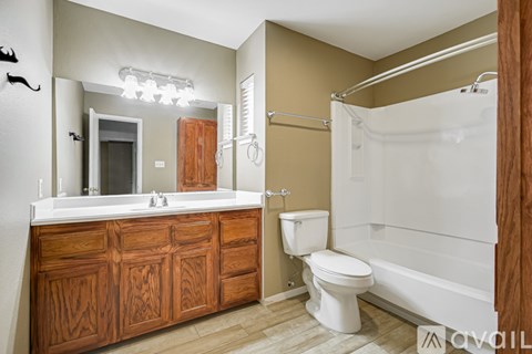 A bathroom with a wooden vanity and white fixtures.