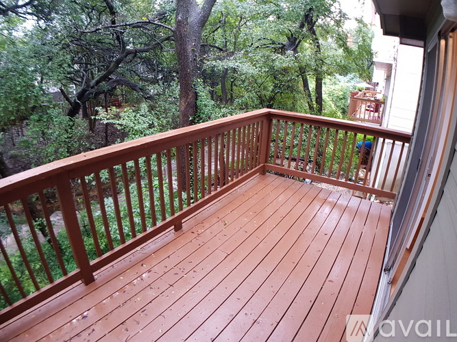 A wooden deck with a railing and trees in the background.