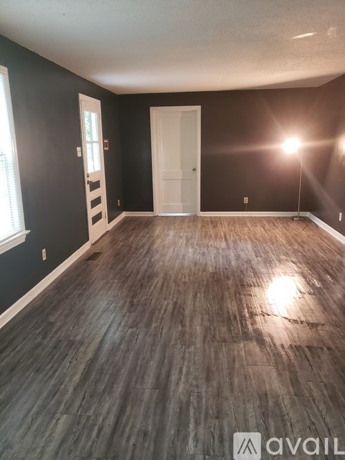 A room with dark wood flooring and a white door.