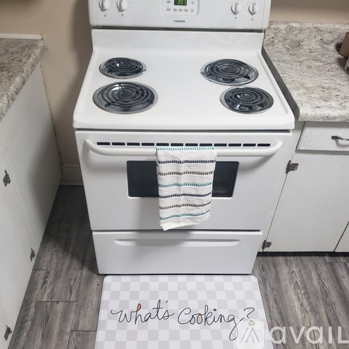 A white stove with a towel hanging on the oven door.